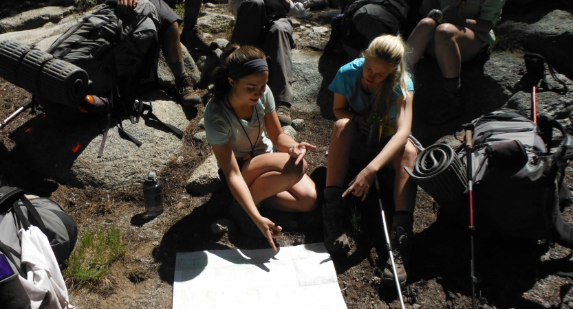 outward bound students take a break from backpacking to look at a map